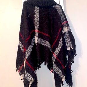 A rolled turtleneck accents the relaxed fit while fringe tassels finish